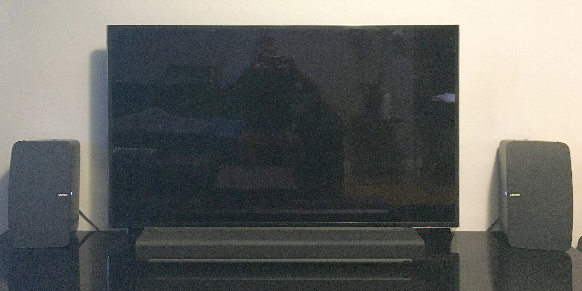 A soundbar under a TV with two side speakers