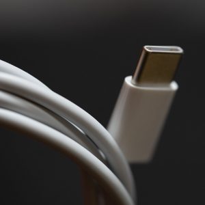 طرف كابل USB‑C أبيض، لقطة قريبة على خلفية داكنة